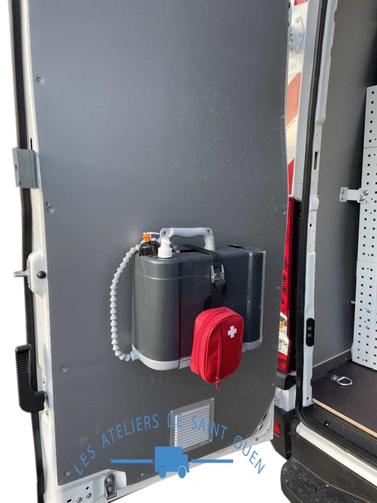 Bidon lave main avec pompe et une trousse de secours installé sur la porte arrière d'un fourgon
