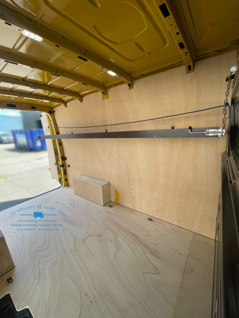 Véhicule aménagé d'un habillage bois avec étagère relevable gauche en cp filmé brun clair